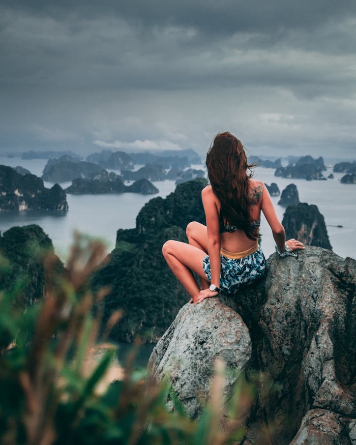 A woman enjoying the breathtaking view of Ha Long Bay from a rocky mountain top in Quảng Ninh, Vietnam.