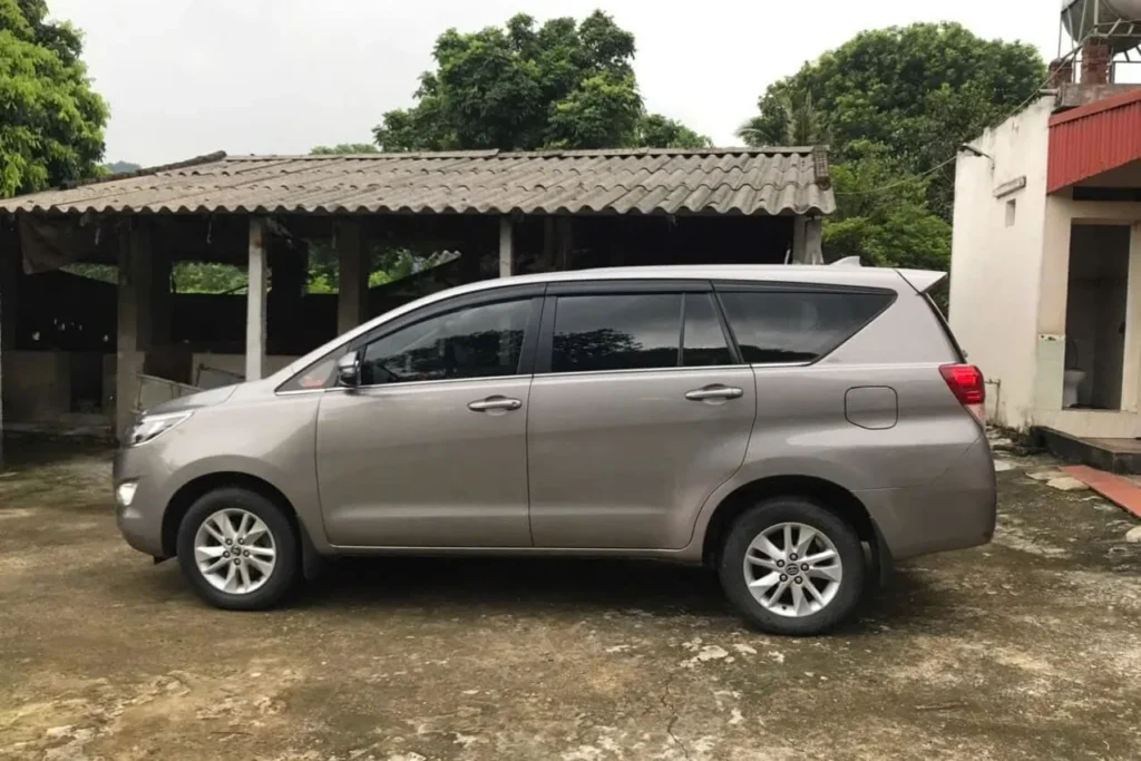 A silver 7-seater SUV parked at a rural village rest stop in Vietnam.
