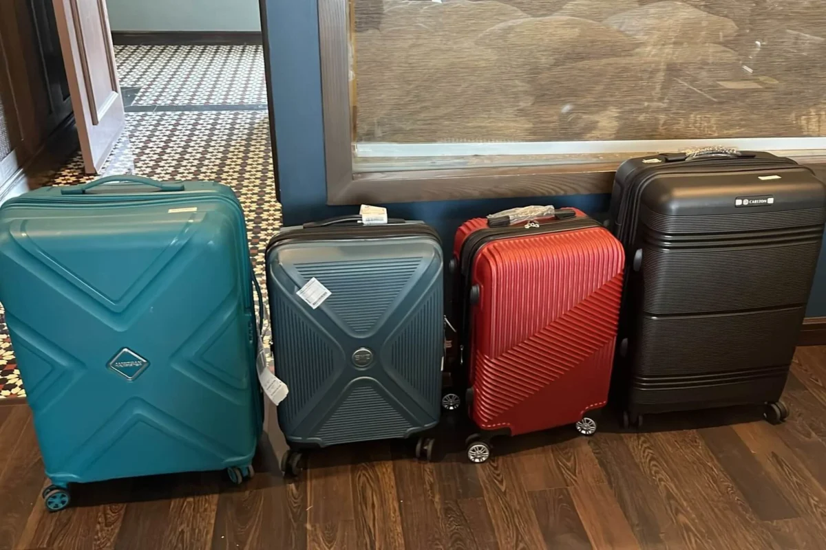 Four large hard-shell suitcases lined up at an airport hotel lobby.