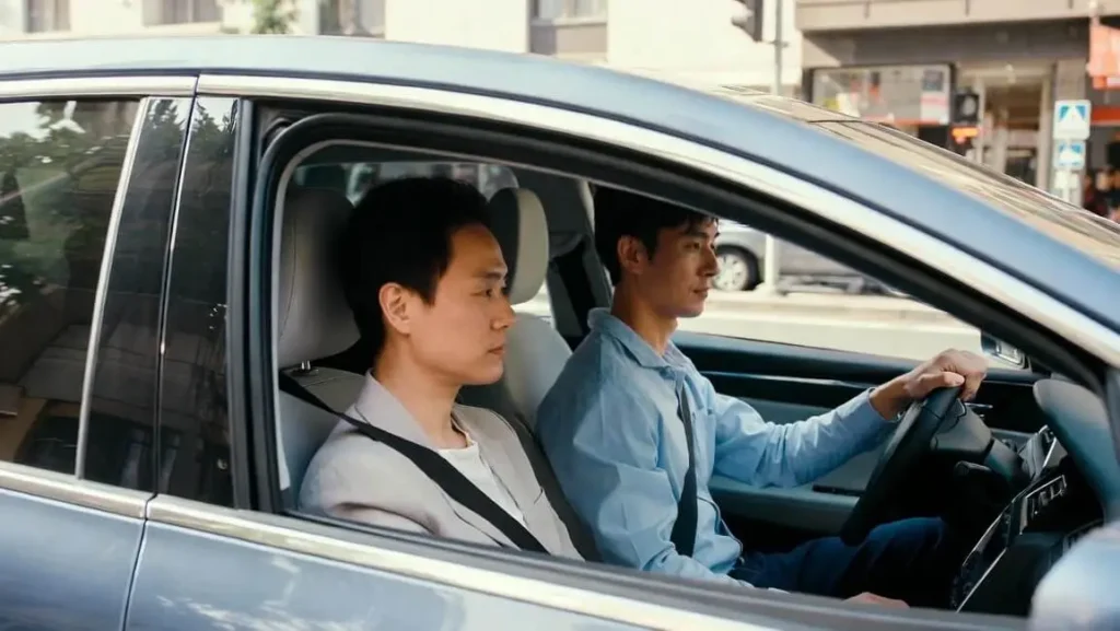 View from inside a private car transfer showing a professional driver and passenger traveling through a Vietnamese city.
