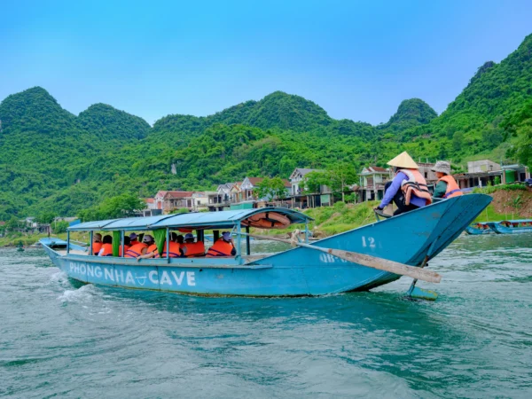 Private driver Phong Nha service driving clients past the limestone cliffs and river entrance of the Phong Nha caves.