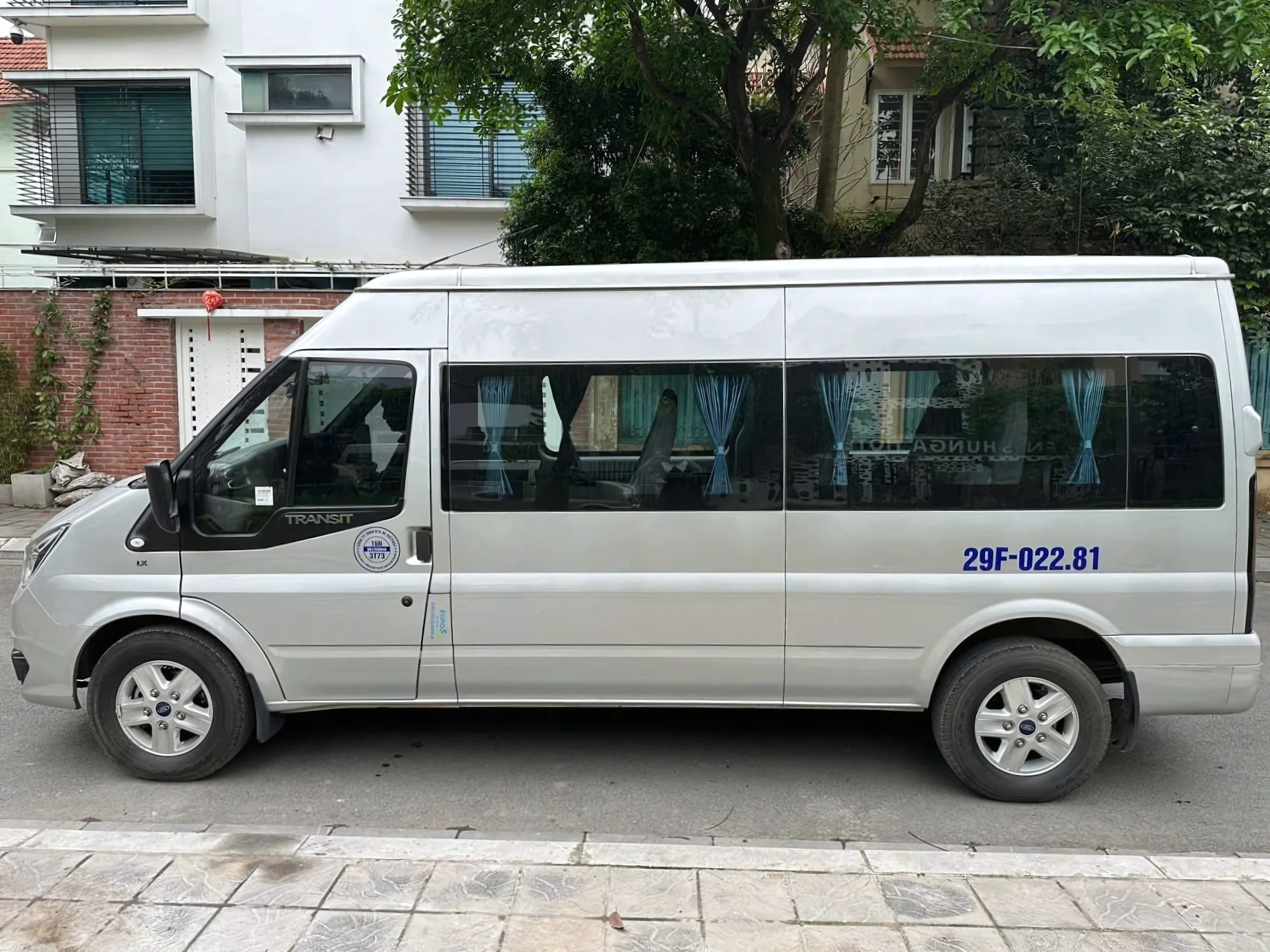 16-seat private van with doors open at a hotel entrance in Sapa