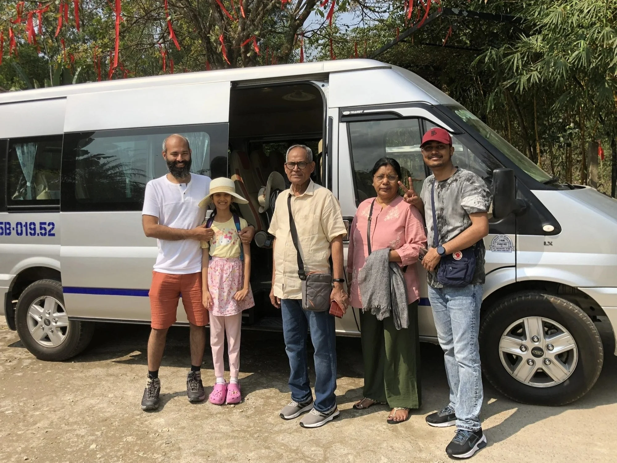 Multi-generational family beside a 16-seat Private Vietnam van — one vehicle price