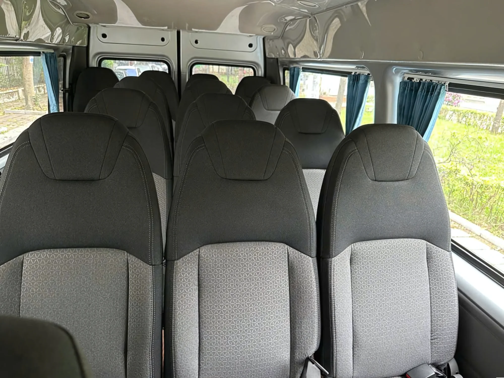 Full passenger cabin with privacy curtains inside a 16-seat private van