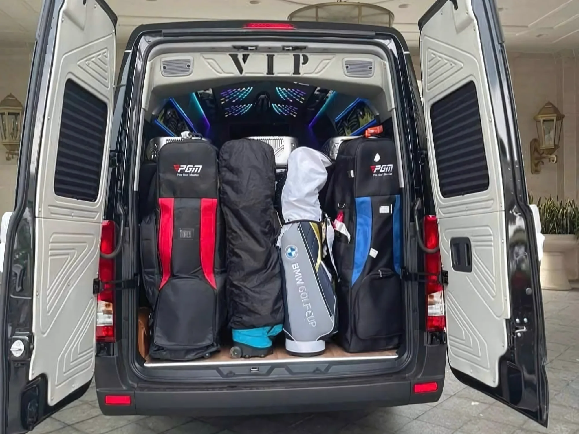 Open rear cargo doors of a 16-seat private van — luggage for a full group
