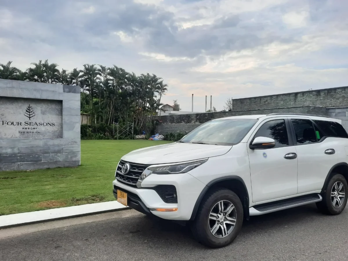 White 7-seat SUV at a resort entrance for the Hanoi to Ha Long Bay transfer