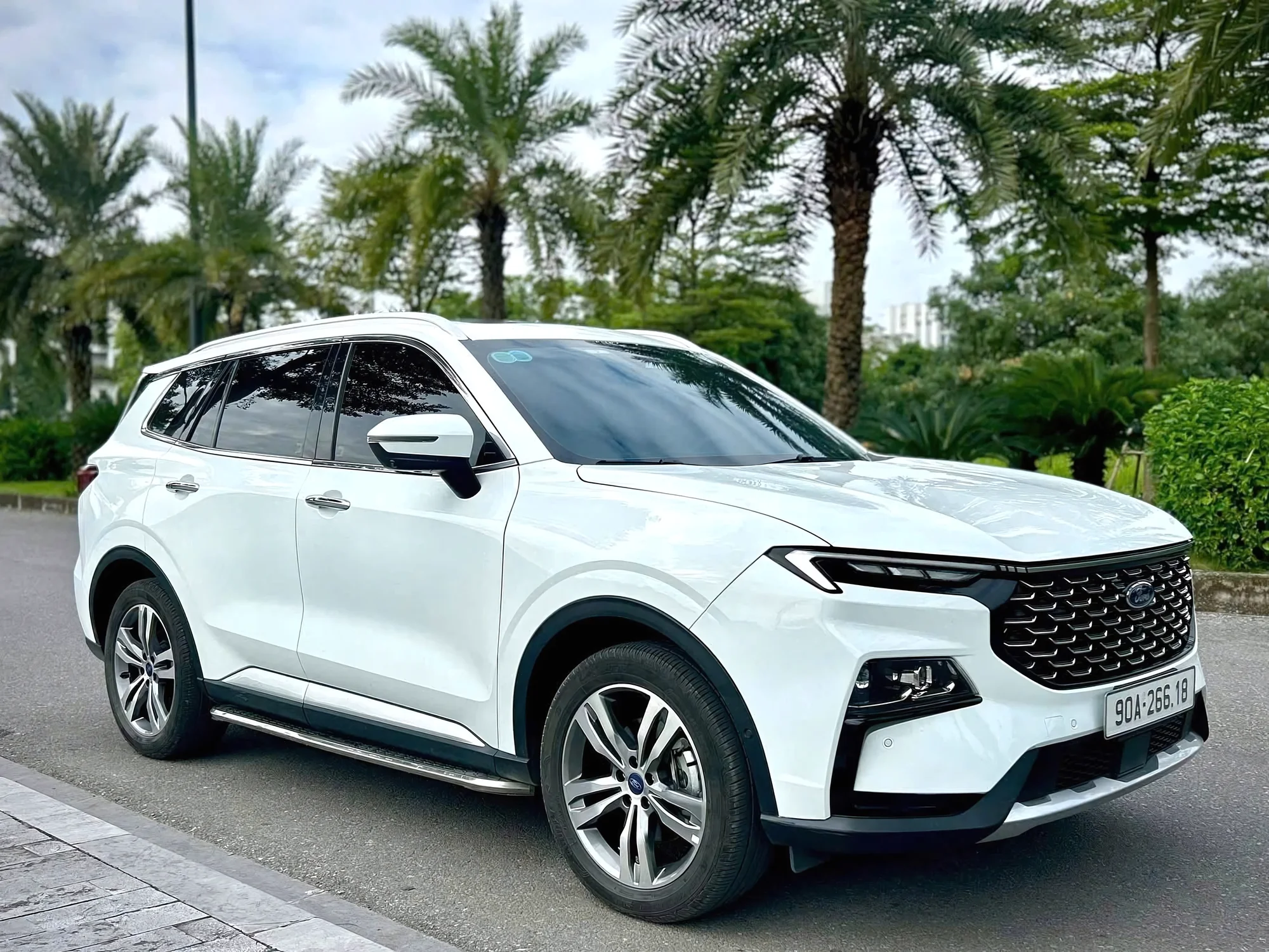 Modern white 7-seat SUV with driver on a Vietnamese city street