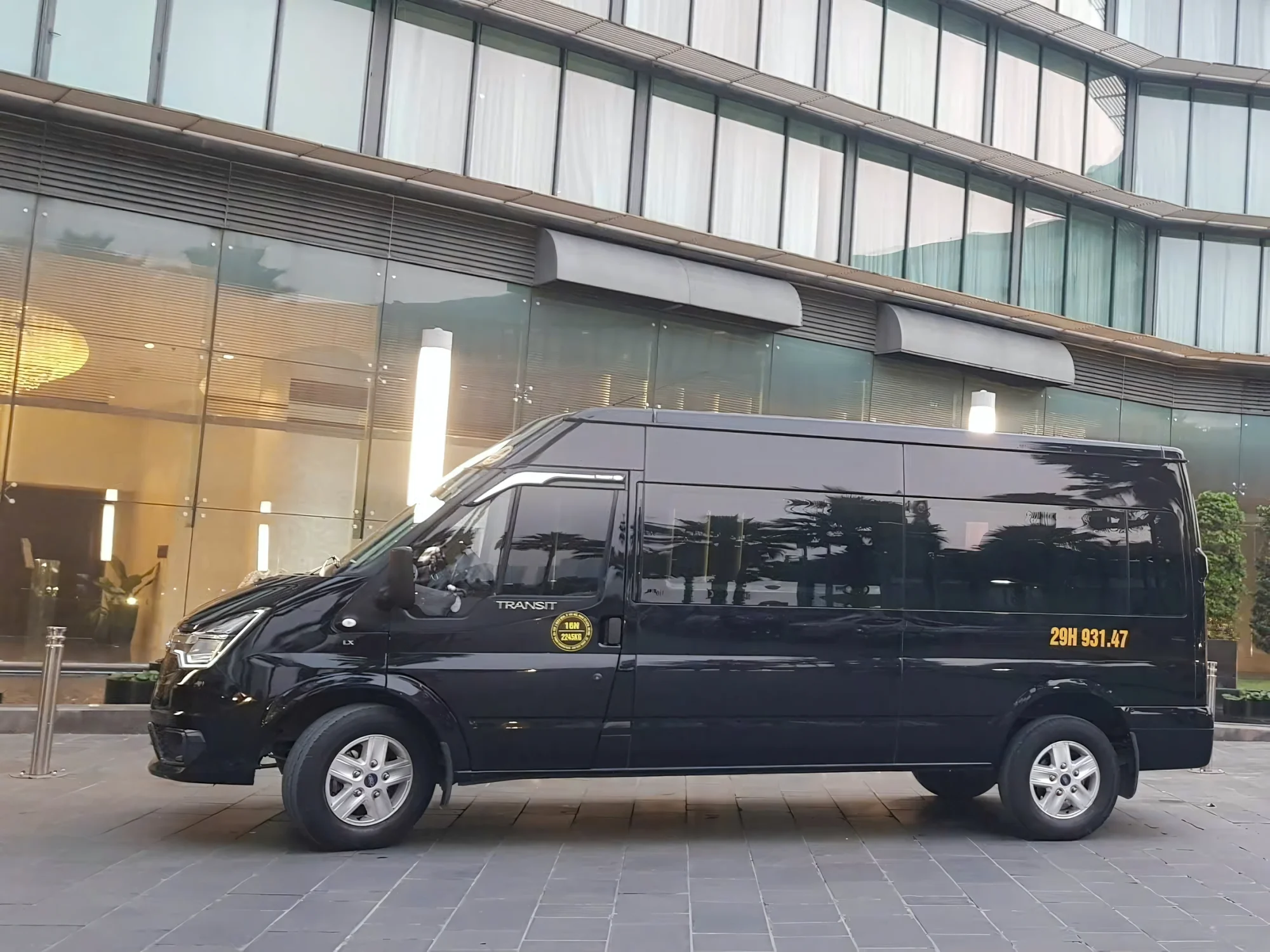 Black 9-seat VIP van at a modern building for a corporate transfer