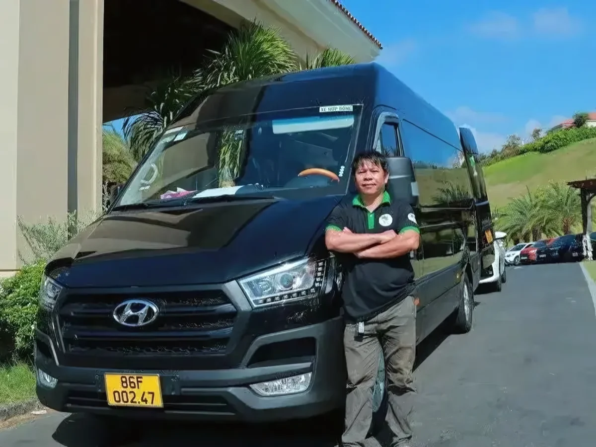 Uniformed Private Vietnam driver standing with a black VIP van at a resort