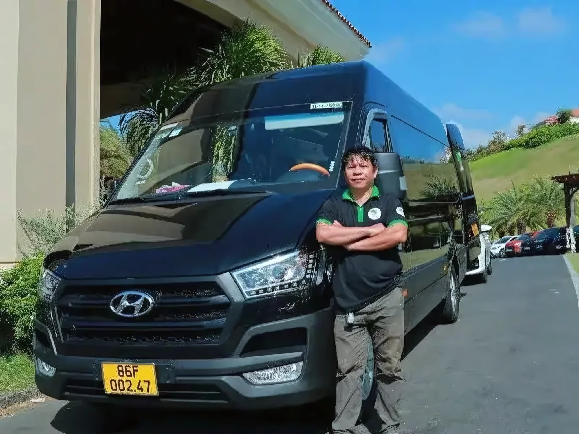 Uniformed Private Vietnam driver standing with a black VIP van at a resort