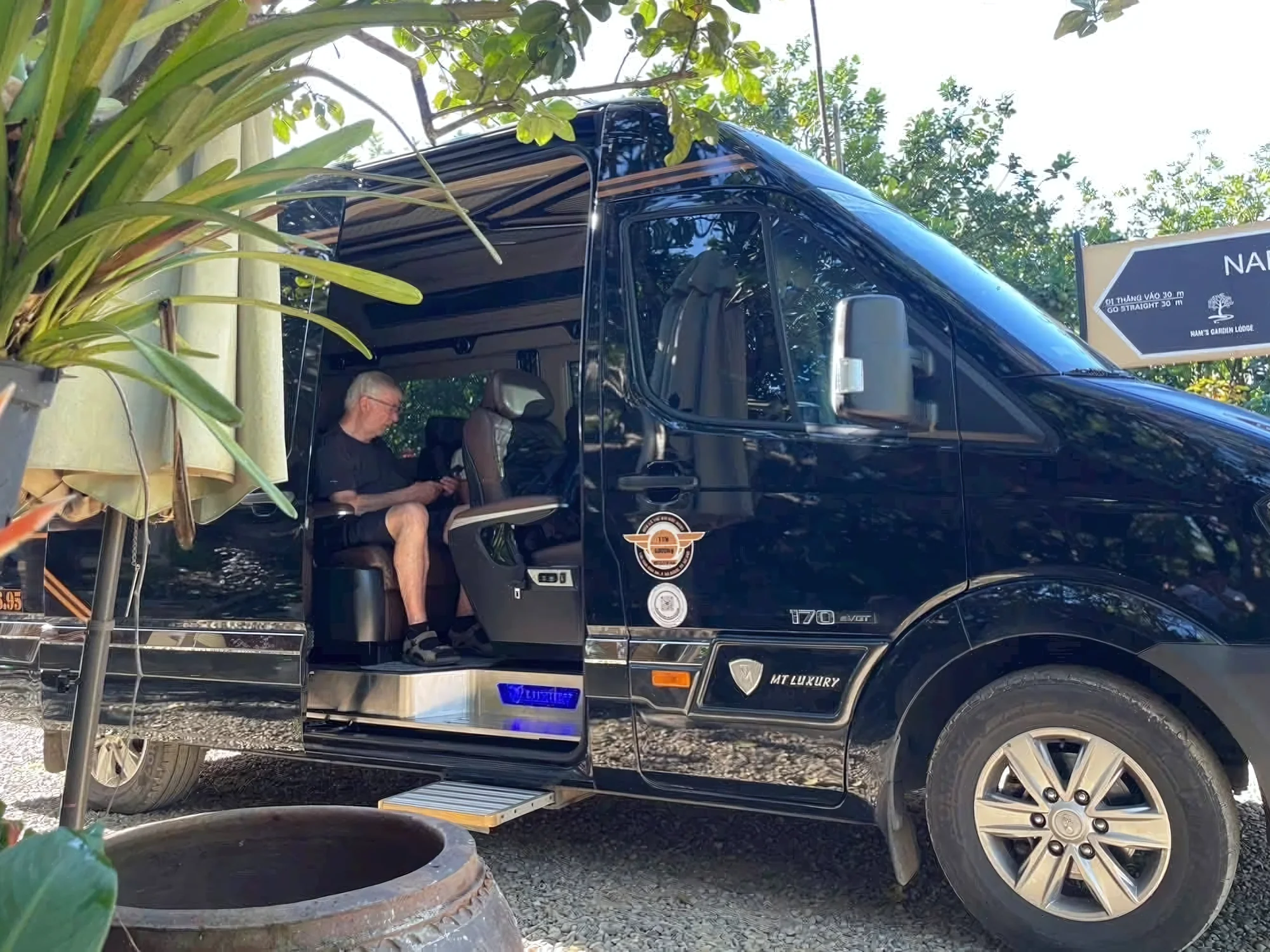 Senior traveller seated in a VIP private van with door open at a resort