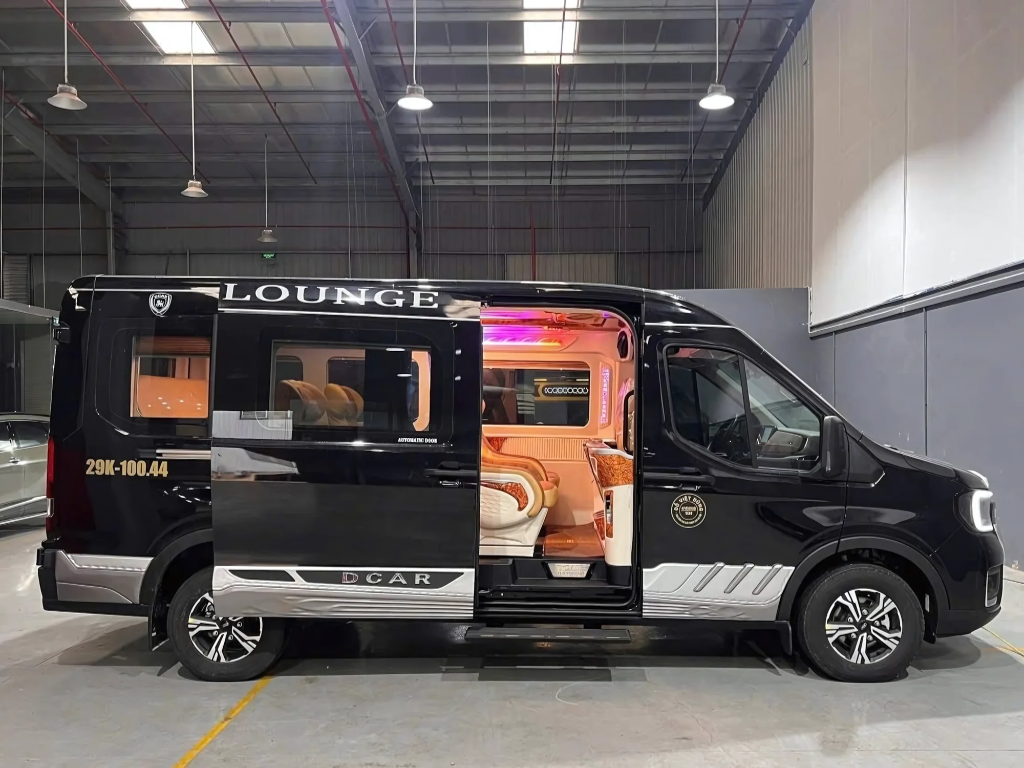 Black VIP lounge van with automatic sliding doors fully open — orange interior