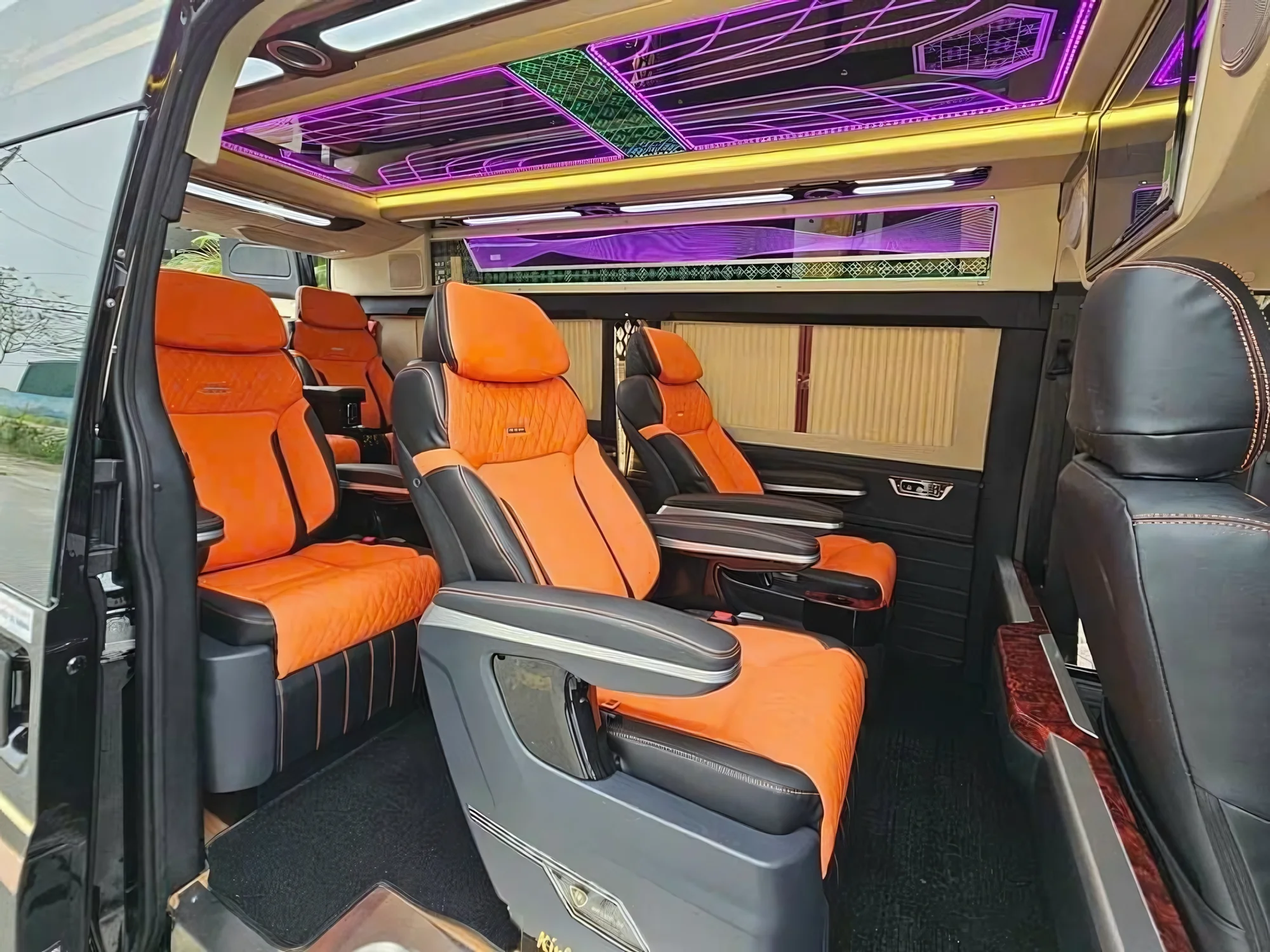 Orange leather captain seats under purple LED ambient lighting in a VIP van