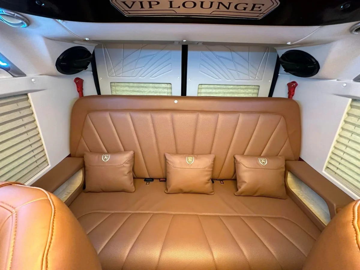 Brown leather last-row and wide central aisle inside a VIP private van