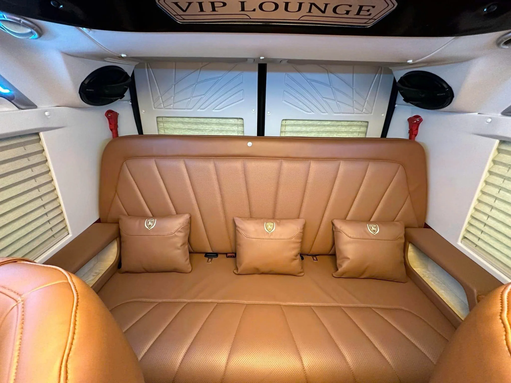 Brown leather last-row and wide central aisle inside a VIP private van