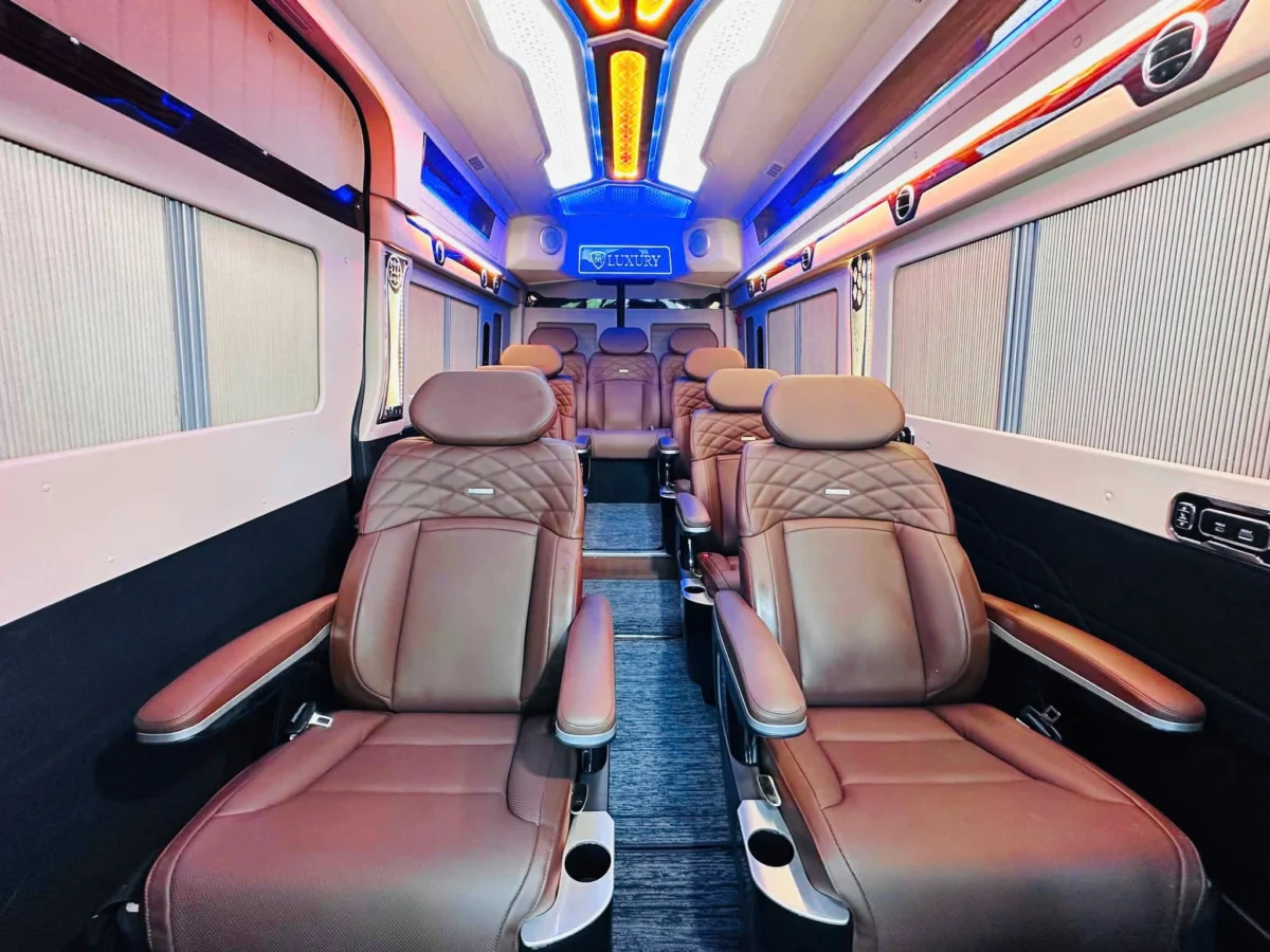Brown leather captain seats under blue and orange LED ceiling — VIP lounge van
