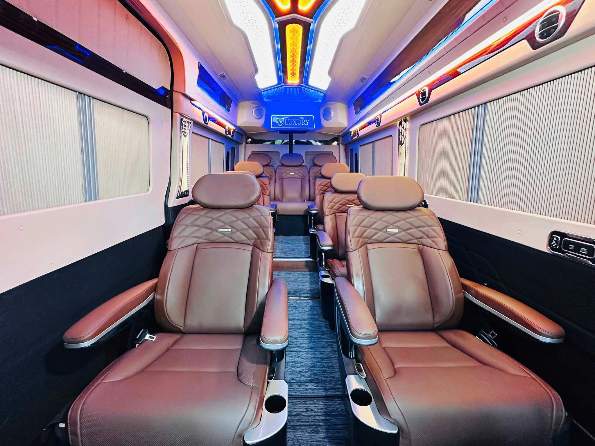Brown leather captain seats under blue and orange LED ceiling — VIP lounge van