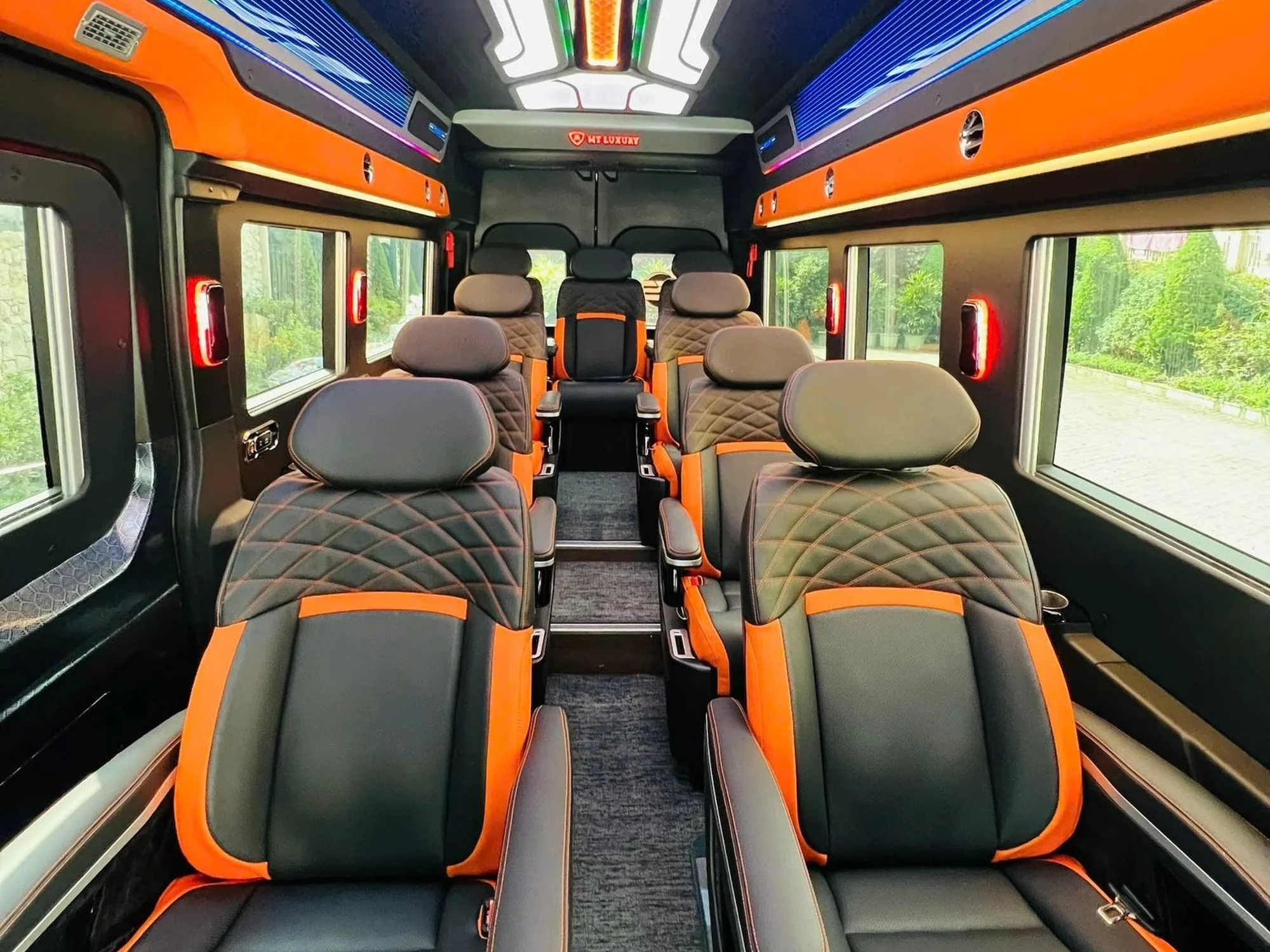 Black and orange leather seats under multi-colour LED ceiling in a VIP van