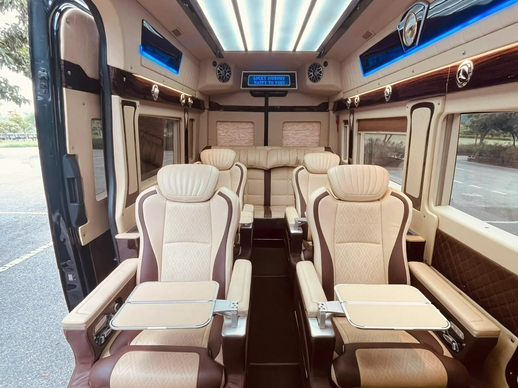 Beige leather seats with fold-down tray tables and panoramic sunroof in a VIP van