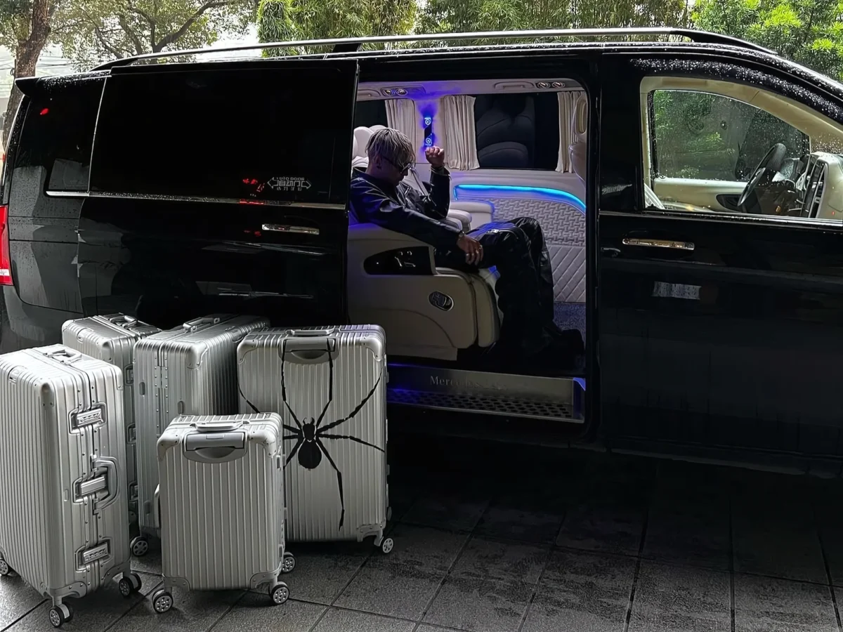 Aluminum suitcases unloaded curbside from a black VIP van with neon interior lighting, demonstrating a private transfer vietnam service.