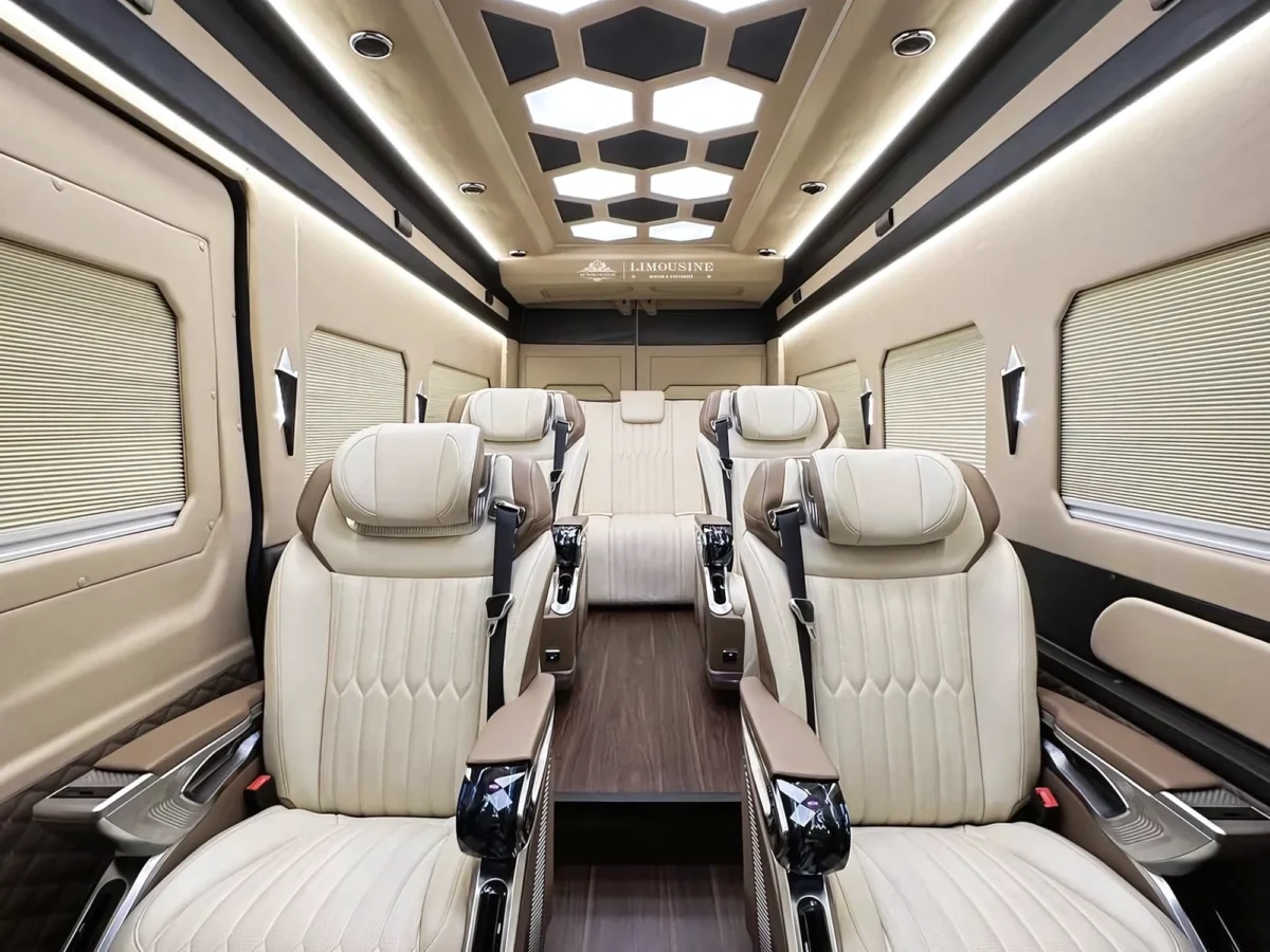 Symmetrical view inside a premium 9-seat Dcar limousine with cream leather reclining seats and wood floors, used for private car hire vietnam and high-end group transfers.